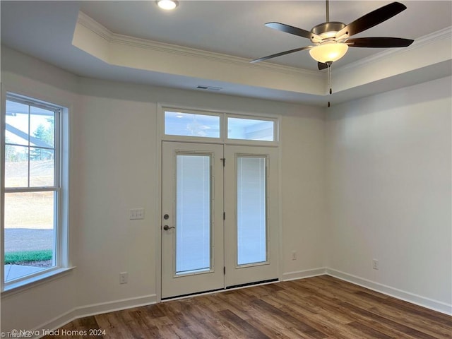 doorway with dark wood-style floors, a tray ceiling, ornamental molding, and baseboards