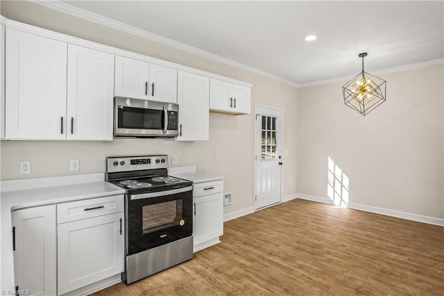 kitchen with ornamental molding, appliances with stainless steel finishes, decorative light fixtures, light countertops, and white cabinetry