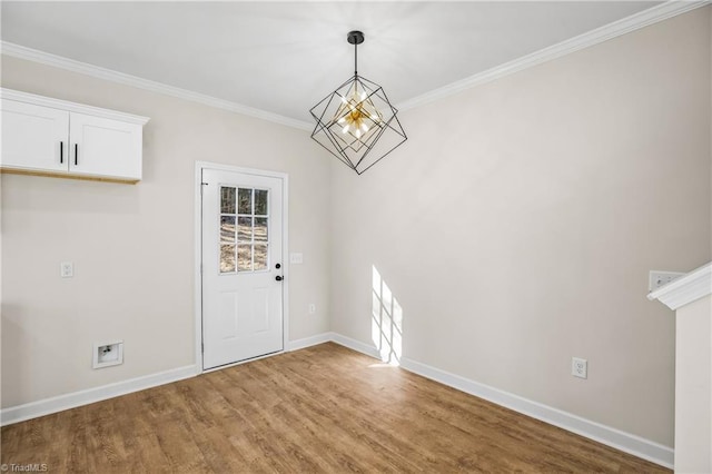 unfurnished dining area with crown molding, an inviting chandelier, wood finished floors, and baseboards