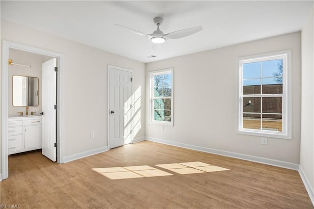 unfurnished bedroom with light wood-type flooring, connected bathroom, baseboards, and a sink