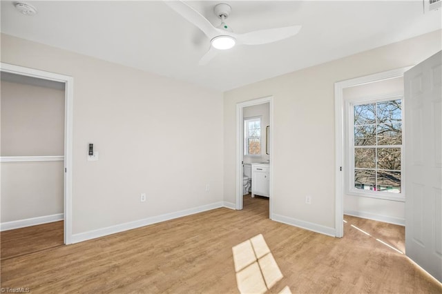 unfurnished bedroom with light wood finished floors, a ceiling fan, baseboards, and connected bathroom