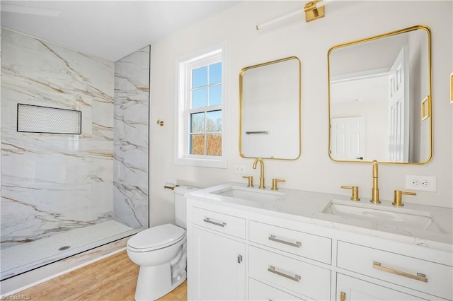 full bath with double vanity, wood finished floors, a sink, and toilet