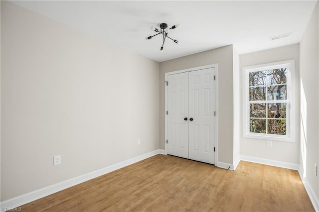 unfurnished bedroom with light wood finished floors, a closet, visible vents, and baseboards