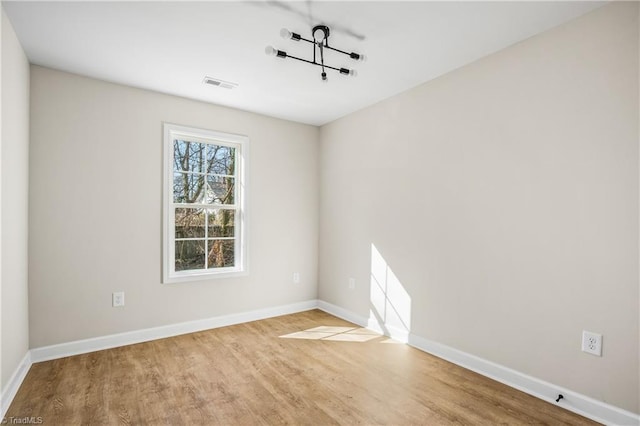 unfurnished room with wood finished floors, visible vents, and baseboards