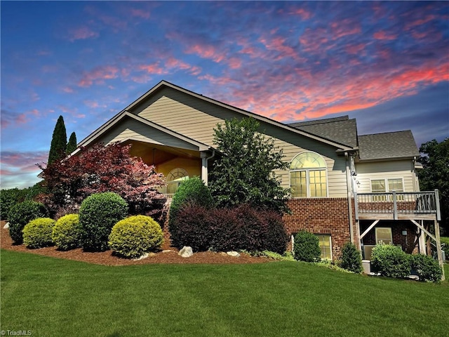 4302 Mossy Wood Cir, Greensboro, NC 27409 - property exterior at dusk featuring brick siding, a yard, and a wooden deck