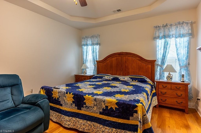 4036 Eastside Ct, Winston-Salem, NC 27127 - bedroom featuring light wood-type flooring, a tray ceiling, and a ceiling fan