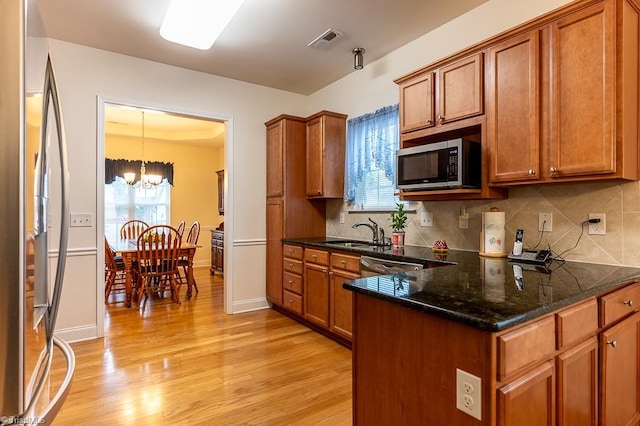 4036 Eastside Ct, Winston-Salem, NC 27127 - kitchen with stainless steel appliances, brown cabinetry, a sink, and light wood-type flooring