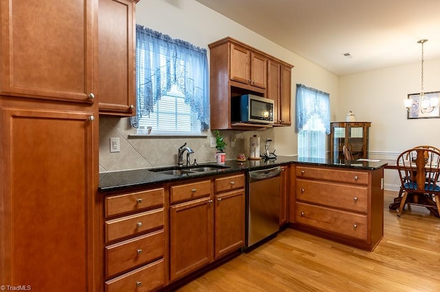 4036 Eastside Ct, Winston-Salem, NC 27127 - kitchen with stainless steel appliances, a sink, light wood-style floors, a peninsula, and decorative backsplash