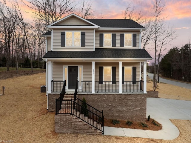 traditional home with a porch and a shingled roof