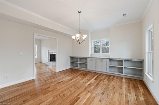 unfurnished dining area with visible vents, baseboards, a premium fireplace, and light wood finished floors