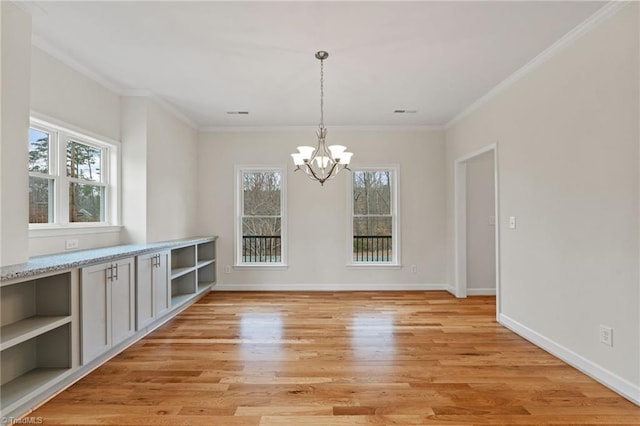 unfurnished dining area with plenty of natural light, light wood-style floors, baseboards, and a chandelier