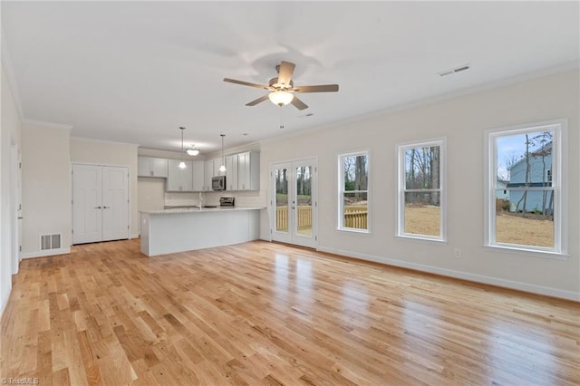 unfurnished living room with visible vents, baseboards, ornamental molding, french doors, and light wood-style floors