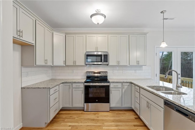 kitchen featuring visible vents, light wood-style flooring, a sink, light stone counters, and stainless steel appliances