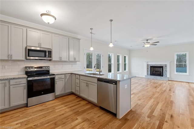 kitchen with gray cabinetry, ornamental molding, a sink, a peninsula, and appliances with stainless steel finishes