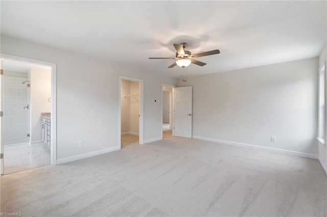 unfurnished bedroom with a spacious closet, baseboards, light carpet, and a closet