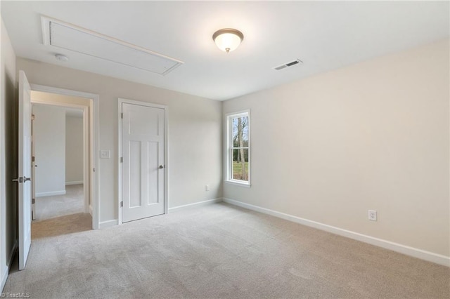 unfurnished bedroom with baseboards, visible vents, attic access, and carpet