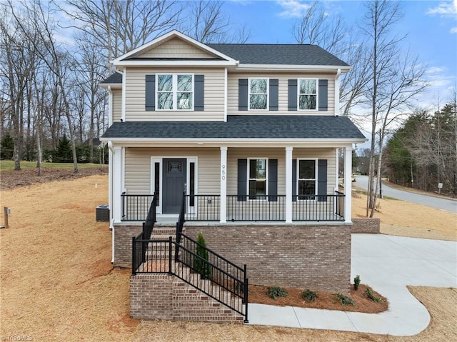 view of front of home with central AC unit, roof with shingles, and a porch