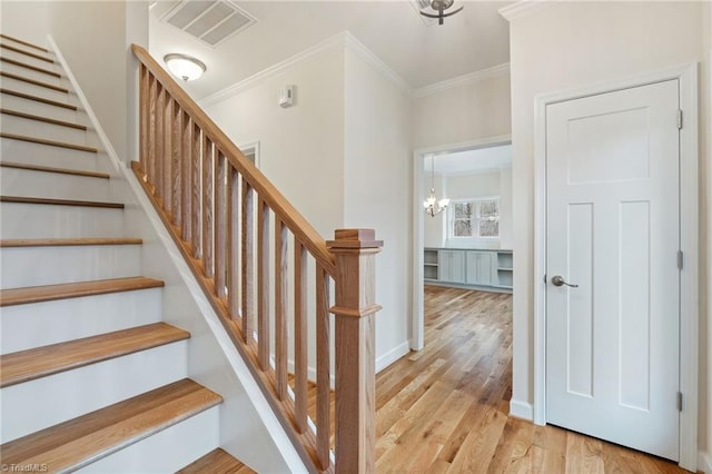 staircase with visible vents, ornamental molding, baseboards, and wood finished floors