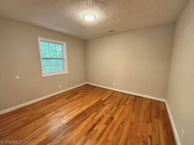 empty room with hardwood / wood-style floors and a textured ceiling