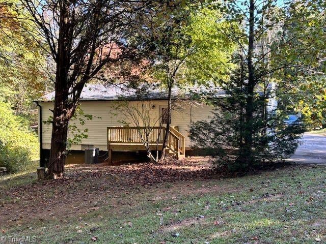 view of side of home with a yard, central air condition unit, and a deck