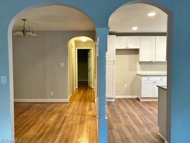 kitchen with hardwood / wood-style flooring, a notable chandelier, hanging light fixtures, and white cabinets