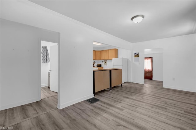 kitchen with crown molding, light hardwood / wood-style flooring, white fridge, and light brown cabinets