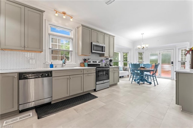 3401 Lochurst Ct, Pfafftown, NC 27040 - kitchen featuring appliances with stainless steel finishes, gray cabinetry, a sink, a chandelier, and backsplash
