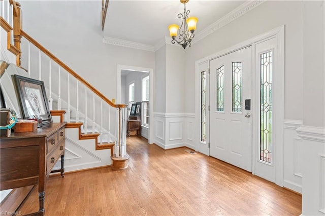 3401 Lochurst Ct, Pfafftown, NC 27040 - entryway featuring a decorative wall, stairway, a chandelier, light wood-style flooring, and wainscoting