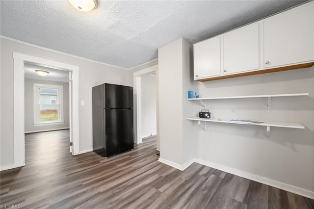 kitchen featuring a textured ceiling, white cabinets, a breakfast bar, dark hardwood / wood-style flooring, and black fridge