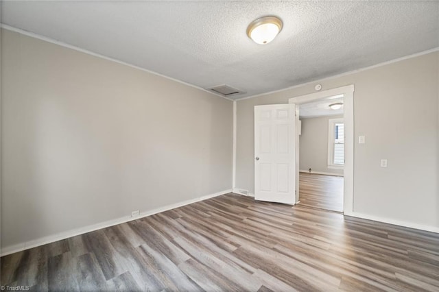 empty room featuring crown molding, wood-type flooring, and a textured ceiling