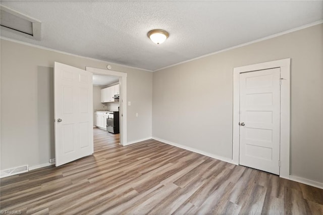 spare room with light hardwood / wood-style flooring, crown molding, and a textured ceiling