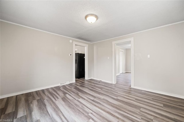 empty room featuring ornamental molding, light hardwood / wood-style flooring, and a textured ceiling