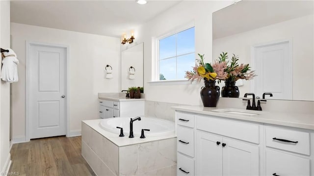 bathroom with vanity, a relaxing tiled tub, and hardwood / wood-style flooring