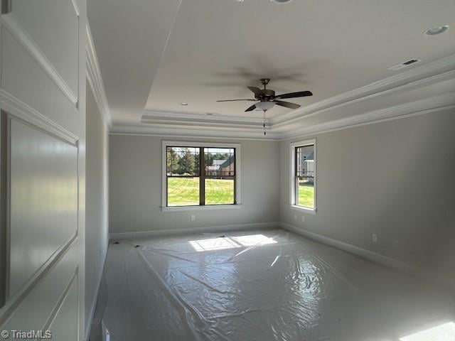 unfurnished room featuring ceiling fan, ornamental molding, and a raised ceiling