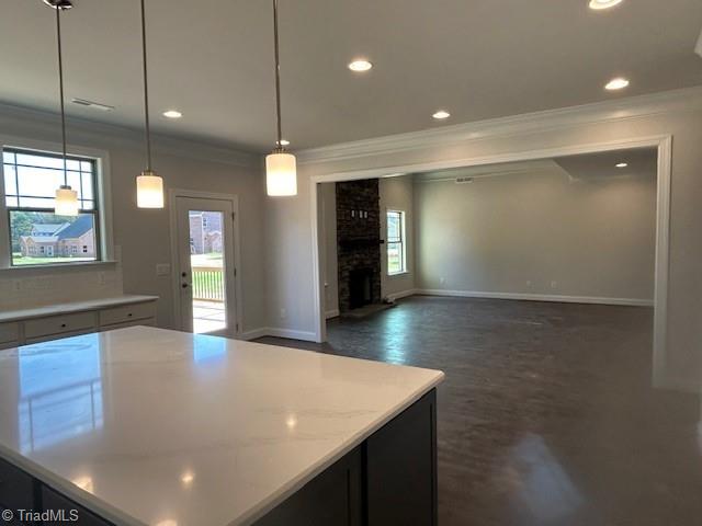 kitchen featuring hanging light fixtures, ornamental molding, and a brick fireplace