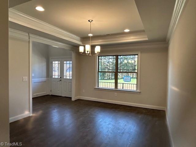 empty room with ornamental molding, dark hardwood / wood-style flooring, and a chandelier