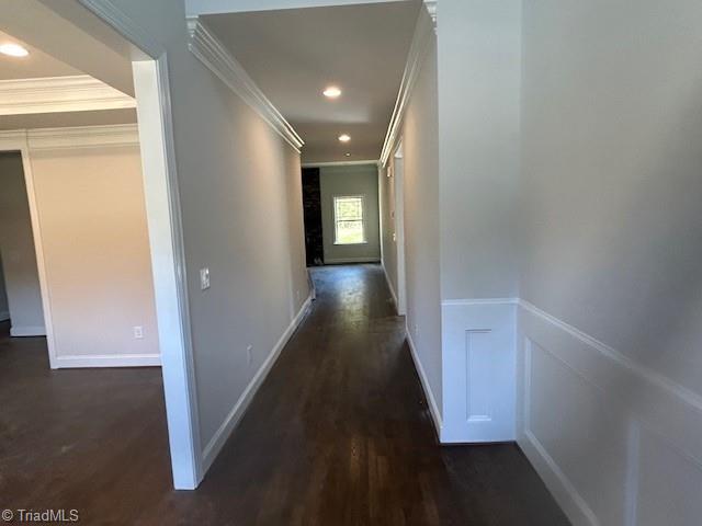 hallway with dark hardwood / wood-style flooring and ornamental molding