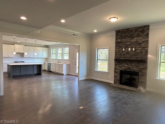 unfurnished living room featuring a fireplace, a wealth of natural light, and crown molding