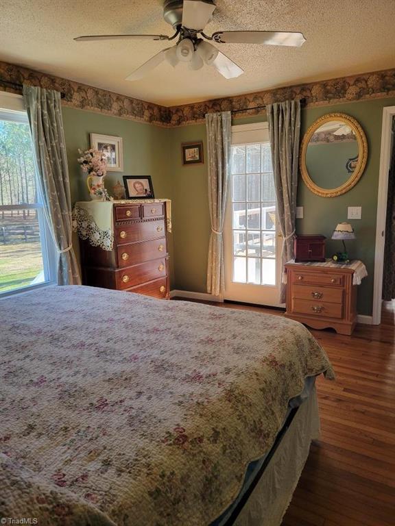 bedroom with a textured ceiling, multiple windows, and wood finished floors