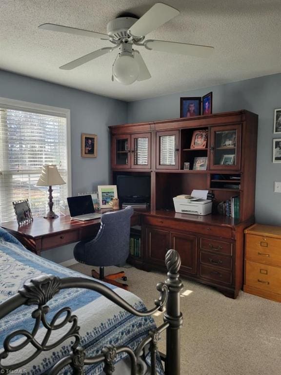 home office with a ceiling fan, light colored carpet, and a textured ceiling