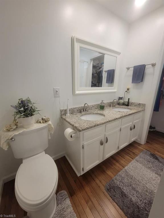 bathroom featuring toilet, hardwood / wood-style flooring, double vanity, and a sink