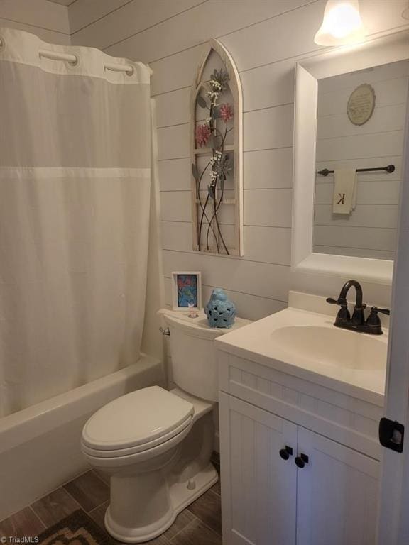 bathroom with wood finish floors, toilet, shower / bath combo with shower curtain, wood walls, and vanity