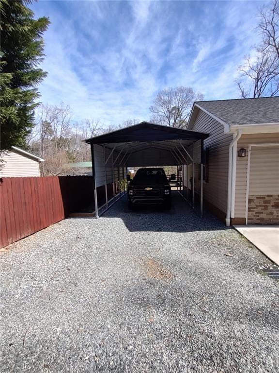 view of parking / parking lot featuring a carport, gravel driveway, and fence