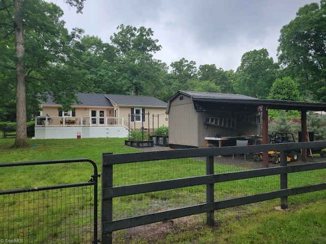 view of front facade with a deck, fence, a front lawn, and an outbuilding