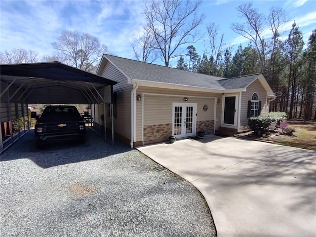 view of front of home with a carport, driveway, french doors, and a shingled roof