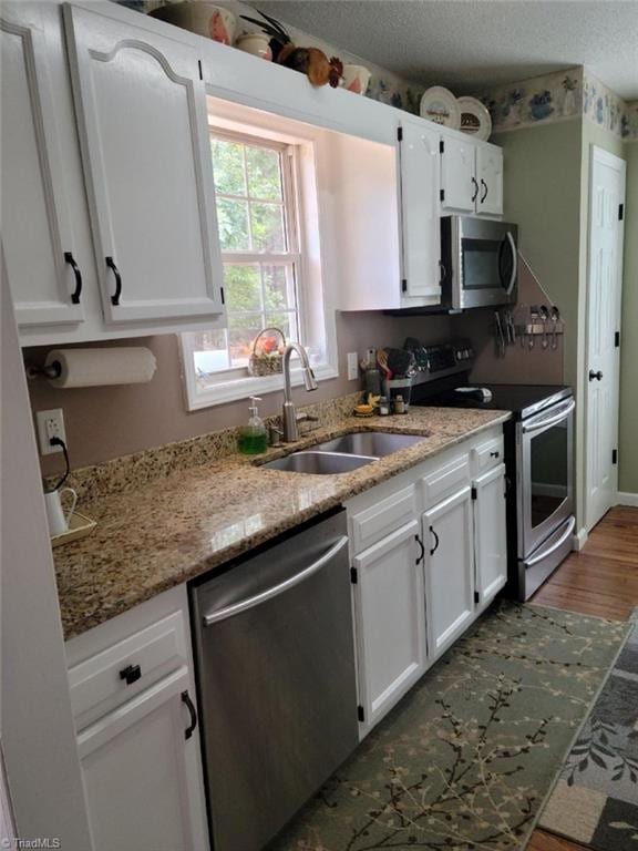 kitchen featuring a textured ceiling, white cabinetry, stainless steel appliances, and a sink