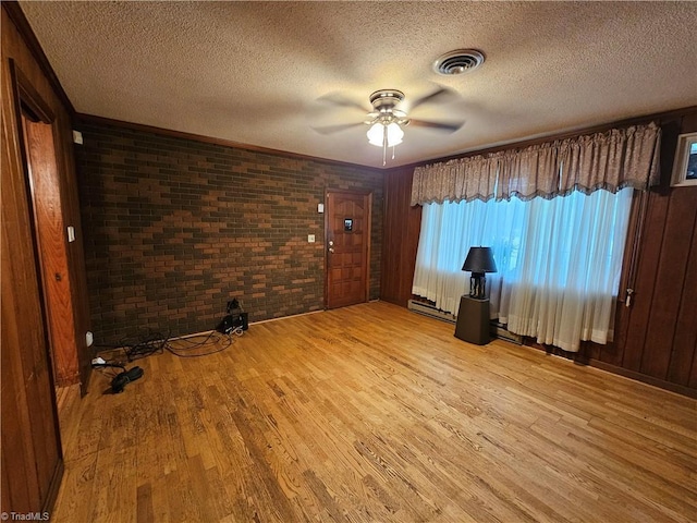 4875 Follansbee Rd, Winston-Salem, NC 27127 - empty room with light wood-type flooring, ceiling fan, brick wall, and a textured ceiling