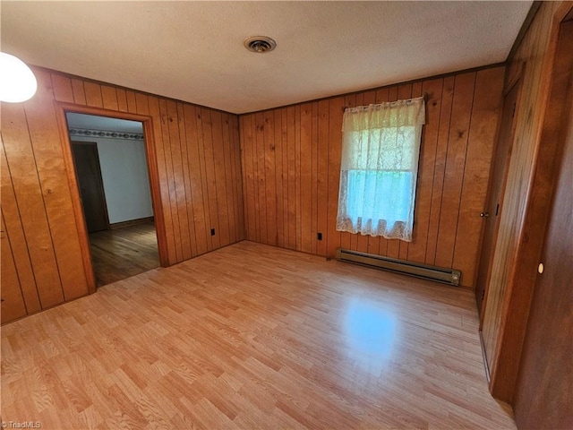 4875 Follansbee Rd, Winston-Salem, NC 27127 - spare room featuring a baseboard heating unit, light wood-style floors, wood walls, and a textured ceiling