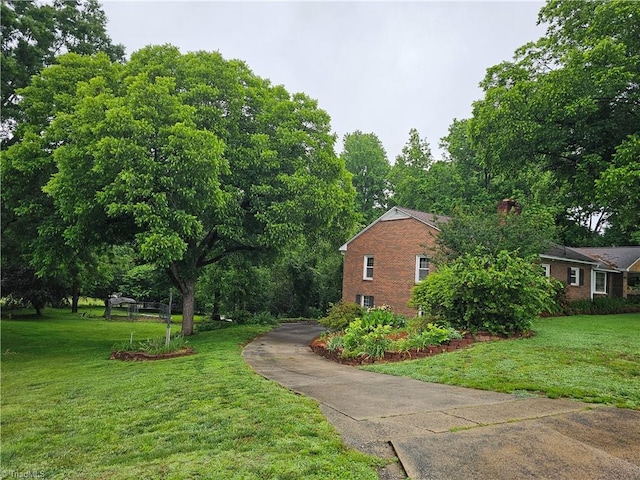4875 Follansbee Rd, Winston-Salem, NC 27127 - view of home's exterior with brick siding, a yard, a chimney, and driveway