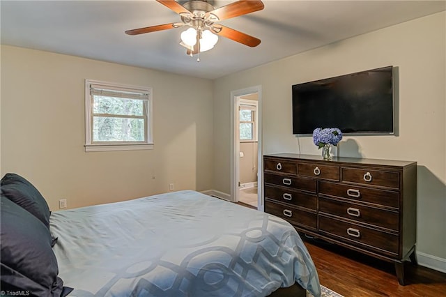 bedroom featuring ensuite bathroom, dark wood finished floors, a ceiling fan, and baseboards